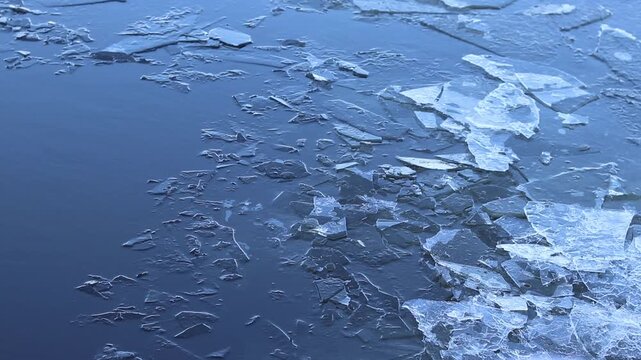 Thin ice on a winter river close-up. The process of melting or freezing of a reservoir in winter. A large ice floe that has broken into smaller pieces near the bank of a river or lake. Ice drift