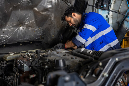Caucasian mechanic is inspecting the diesel truck engine after annual check up in the professional garage and maintenance all the filter and gear for safety driving concept