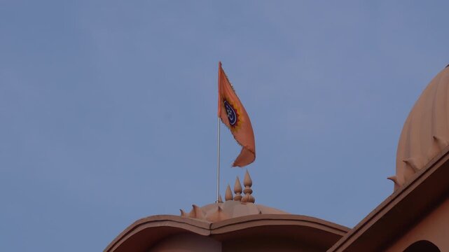 Bhagwa dhwaj flying above hindu temple against blue sky