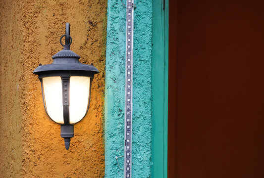 Vintage outdoor wall lantern illuminates textured wall and decorative trim.