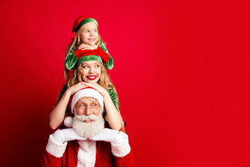 Obraz premium Santa with smiling mother and daughter elves posing together for cheerful Christmas family portrait in festive red and green holiday costumes