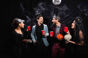 Obraz premium Friends celebrating Halloween with joyful costumes and drinks at a lively party