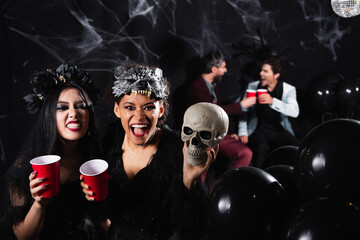 Obraz premium Multicultural female friends celebrate Halloween at a fun costume party