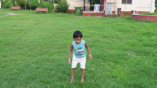 Happy child jumping on green lawn outdoors