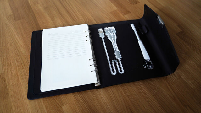 professional notebook with different types of cables and a foldable lamp on the backside, portable charging station, powerbank