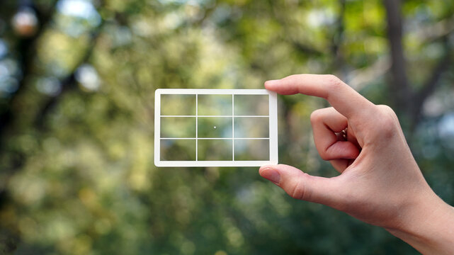 hand holding a transparent card with composition grid