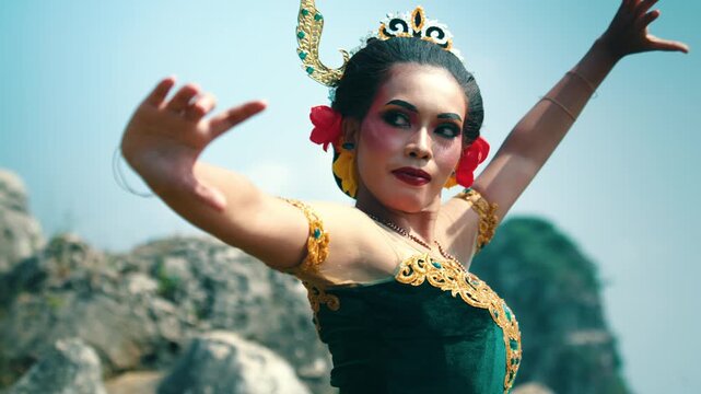 A shot from behind showing a traditional dancer raising her arms gracefully, displaying the details of her hair accessories and costume.