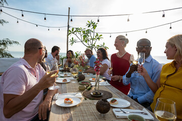 Fototapeta premium Diverse group of men and women sharing drinks at an outdoor dinner