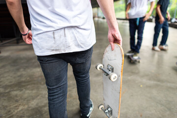 Person holding a skateboard in an urban setting, wearing casual attire. © Rawpixel.com
