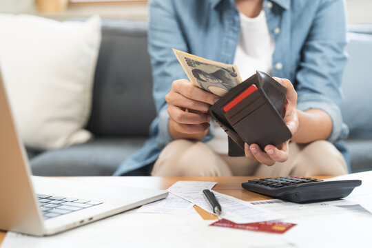 Close up of a person hands taking out banknotes, cash or money from a leather wallet while calculating home budget, planning expense and doing personal finance management.