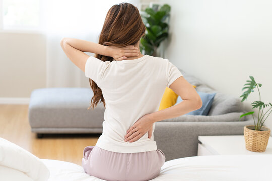 Pain body muscles stiff problem, asian young woman painful back, neck ache from work hand holding massaging rubbing shoulder hurt, sore sitting on bed while wake up at home. Health care and medicine.