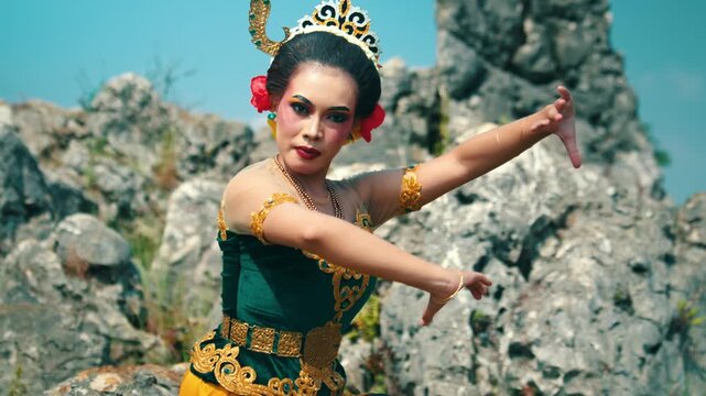 Footage of a female performer executing a traditional dance move by spreading her arms wide, showcasing the elegance of Javanese dance.
