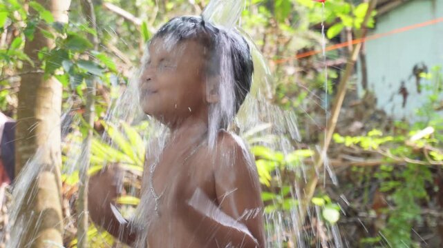 Young child enjoying an outdoor bath with mother