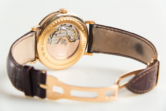 Luxury Breguet Classique wristwatch featuring a rose gold case, silver guilloch&eacute; dial, moonphase indicator, power reserve, and leather strap.