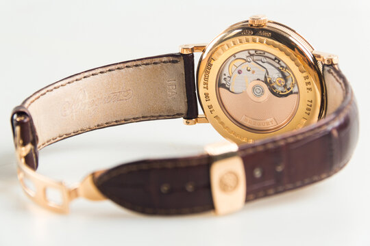 Luxury Breguet Classique wristwatch featuring a rose gold case, silver guilloch&eacute; dial, moonphase indicator, power reserve, and leather strap.