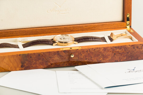 Luxury Breguet Classique wristwatch featuring a rose gold case, silver guilloch&eacute; dial, moonphase indicator, power reserve, and leather strap.