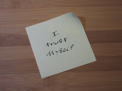 Handwritten I trust myself affirmation on sticky note placed on wooden table