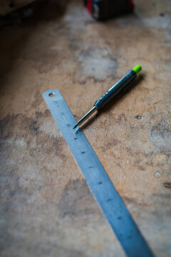 View of a metal ruler and a mechanical pencil resting on a weathered wooden workbench in Looe, Cornwall, United Kingdom.