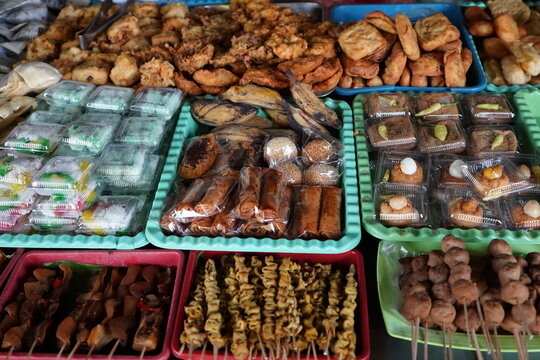 Variety of traditional Indonesian street food snacks and fried dishes displayed on trays at an angkringan stall in Java, featuring quail egg skewers, tofu, tempeh, and authentic local delicacies.food,