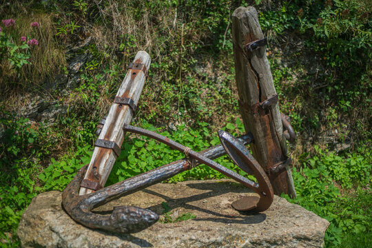 View of an old iron and wooden anchor resting on a stone base in Charlestown, Cornwall, United Kingdom.