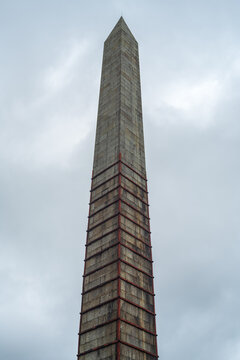 View of the Bodmin Beacon stone obelisk monument rising against a cloudy sky in Bodmin, Cornwall, United Kingdom.