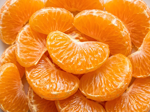 Full frame background of sweet and juicy peeled mandarin orange and clementine segments showcasing vibrant citrus pulp vesicles texture and fresh organic healthy fruit nutrition ready to eat