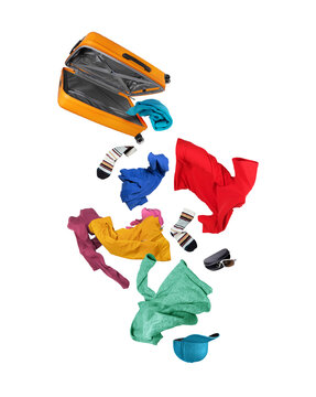 Open orange suitcase in mid-air with colorful casual clothes and accessories falling down