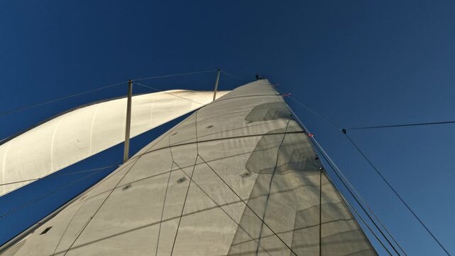 Sailing yacht mast and sail against blue sky