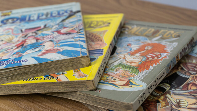 SOUTH KALIMANTAN, INDONESIA - SEPTEMBER 30, 2026: Several volumes of One Piece manga comic books by author Eiichiro Oda are spread diagonally on a wooden table. The front covers illustrate