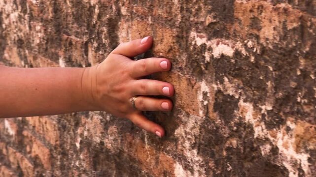 Hand touching ancient wall texture in Rome, close-up historical exploration.