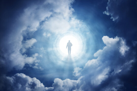 Surreal spiritual scene of a human silhouette standing in a radiant opening above the clouds, surrounded by dramatic sky and heavenly light. Psychology, psychiatry, religion,  mysticism items.