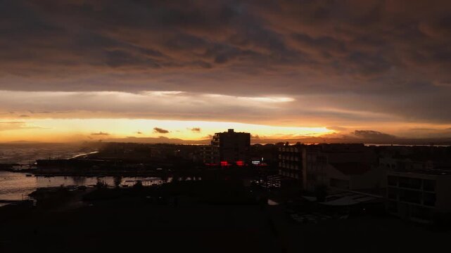 Storm sunset over silhouetted Carnon apartments beside the Mediterranean