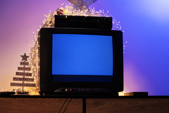 Retro Christmas movie night with CRT television and VCR surrounded by festive lights, star and holiday decorations