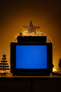 Retro CRT television with VCR and Christmas lights, blue no signal screen in festive holiday interior