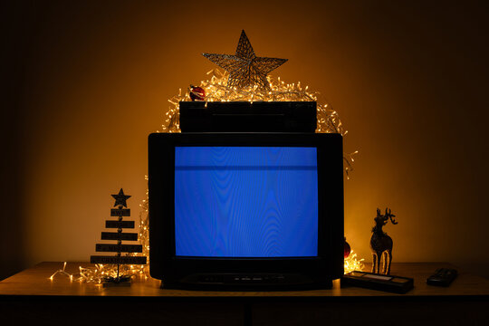 Retro CRT television with VCR and Christmas lights, blue no signal screen in festive holiday interior