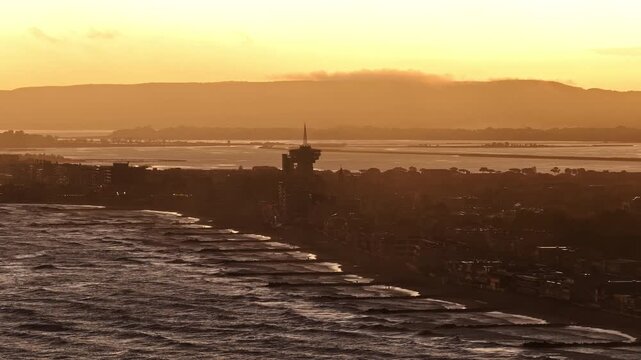 Sunset over Carnon beach groynes tower and lagoon toward hills