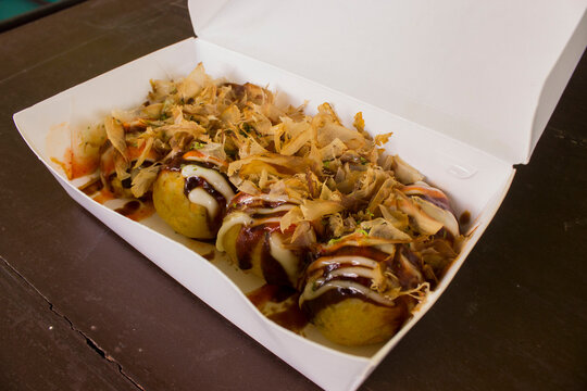 Takoyaki is food Japan, in the form of small balls made from dough flour filled with pieces of octopus. japanese food, isolated in wood background