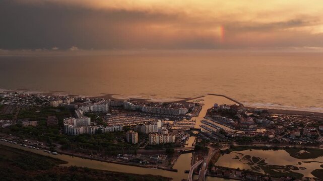 Aerial Carnon port canals and lagoon under a sunset rainbow