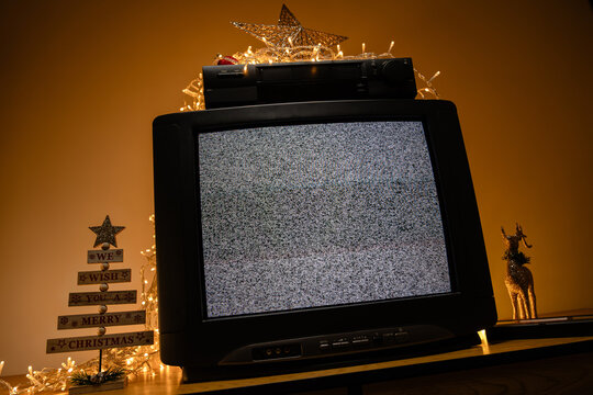 Retro CRT television with VCR and Christmas lights, static noise screen in festive holiday interior
