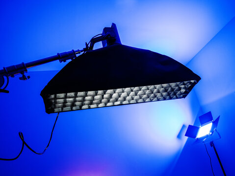 Professional studio lighting setup with large softbox and LED panel under blue ambient light