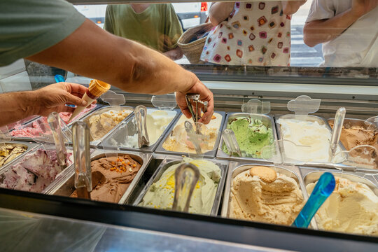 Fresh artisanal gelato being scooped into waffle cone at traditional ice cream shop