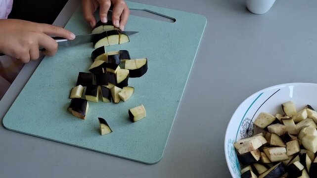 Chopping eggplant on a cutting board in the kitchen