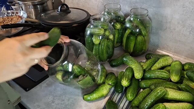 Preparing cucumbers for preservation in a kitchen setting with jars