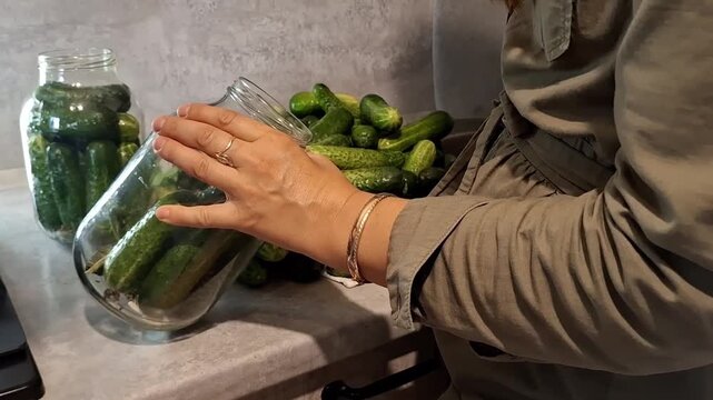 Preparing pickles in the kitchen with fresh cucumbers in jars