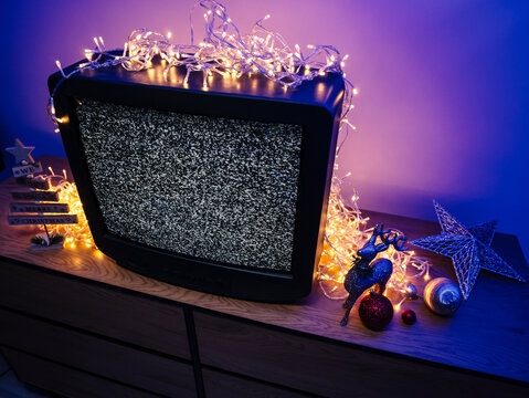 Vintage CRT television with static screen, glowing lights and festive holiday decorations