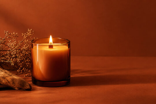glowing scented candle in glass jar with dried flowers for warm new year atmosphere