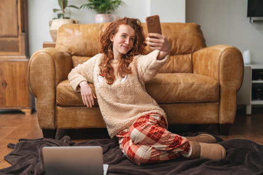 Woman taking a selfie while sitting on the floor in front of a couch