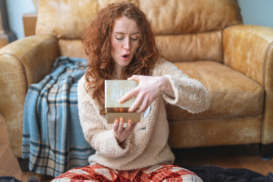 Opening a gift while sitting on the floor in a cozy living room