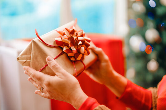 In a cozy indoor setting, a person is holding a wrapped gift with a