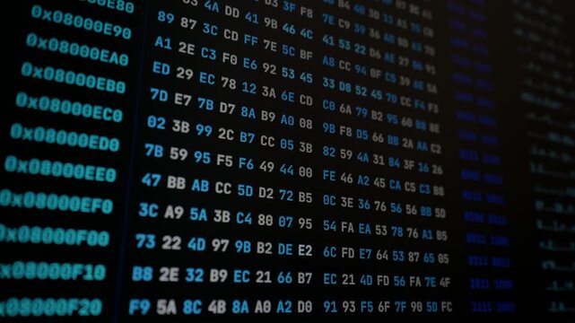 Glowing cyan hexadecimal code and memory addresses scroll across a dark computer monitor close-up. Low-level assembly architecture provides technical context for cybersecurity edits.